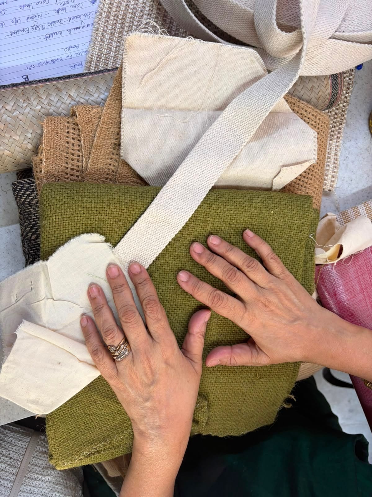 An artisan’s hands laid over swatches of jute, cotton and canvas