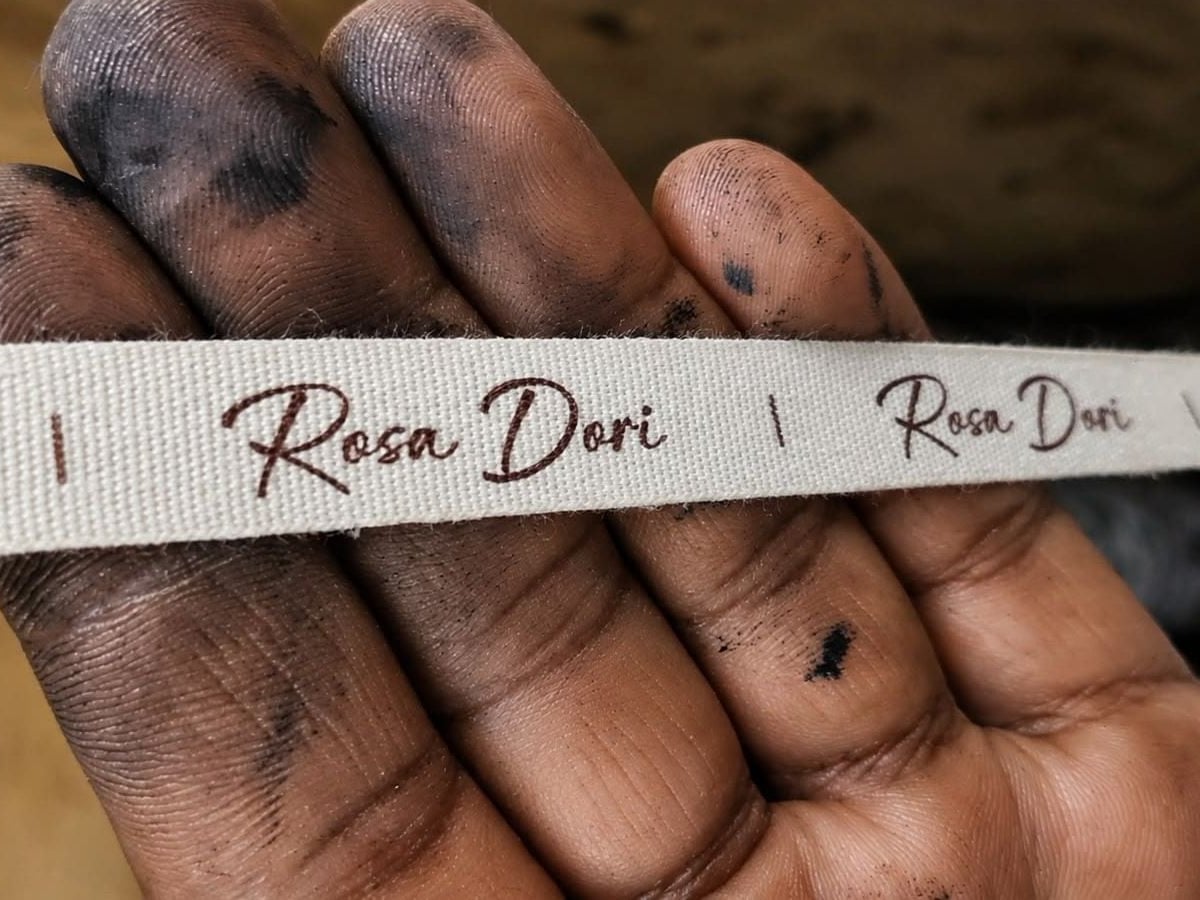 An artisan holding the woven Rosa Dori label